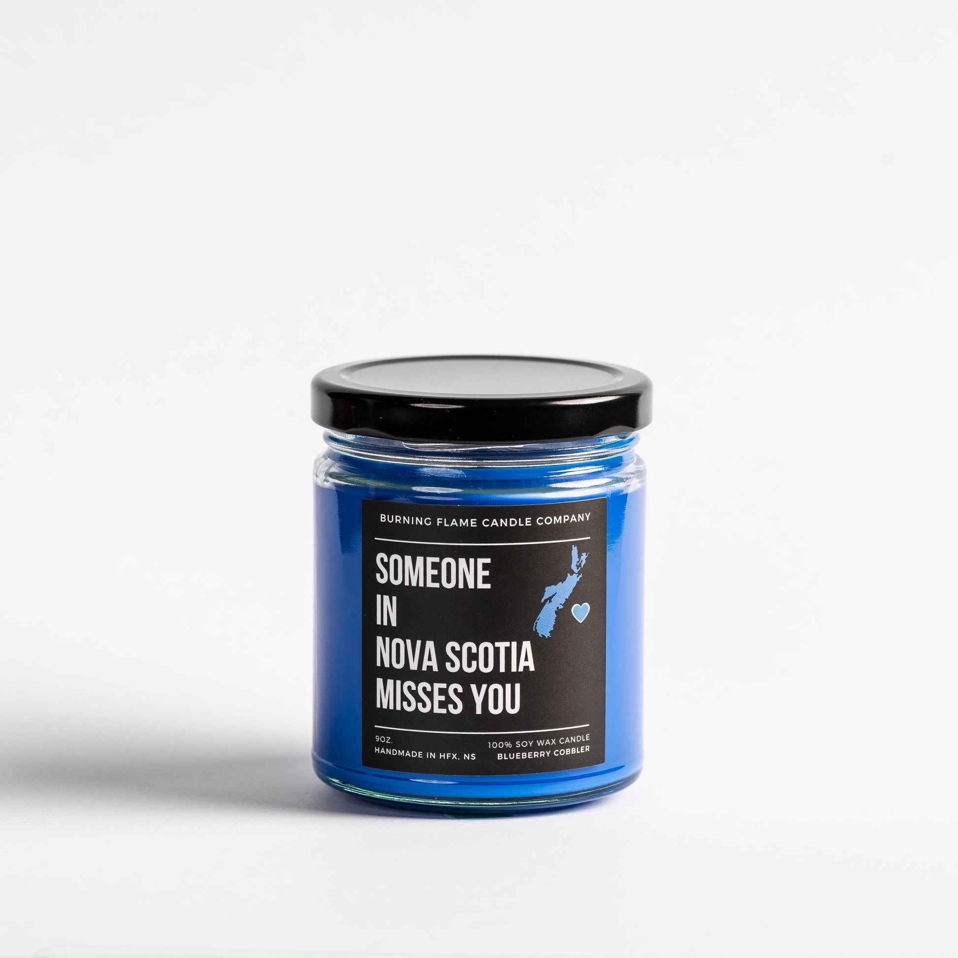 Burning Flame Candle Company’s Someone in NS Misses You blueberry cobbler scented candle in a glass jar with label.