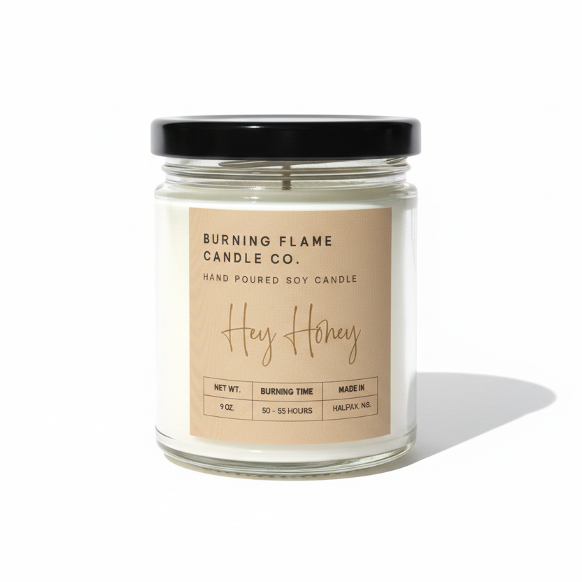 A glass jar candle with a black lid and a beige label reading 'BURNING FLAME CANDLE CO. Hey Honey' on a clean white background.